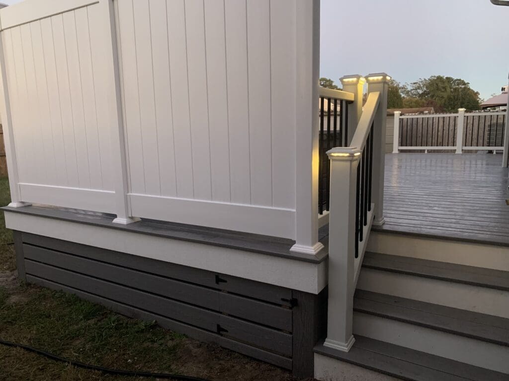 A white fence with black railing and steps.