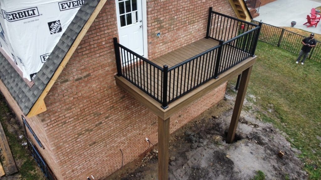 A balcony with black railing and wooden posts.