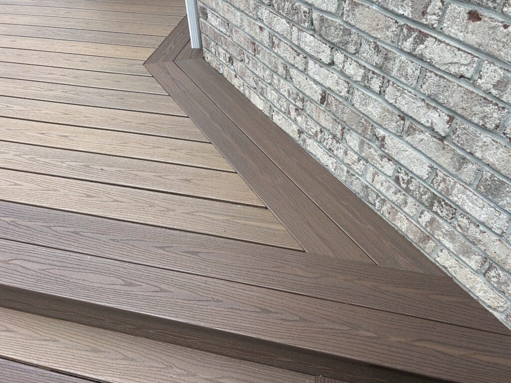 Wooden deck with brick wall background.